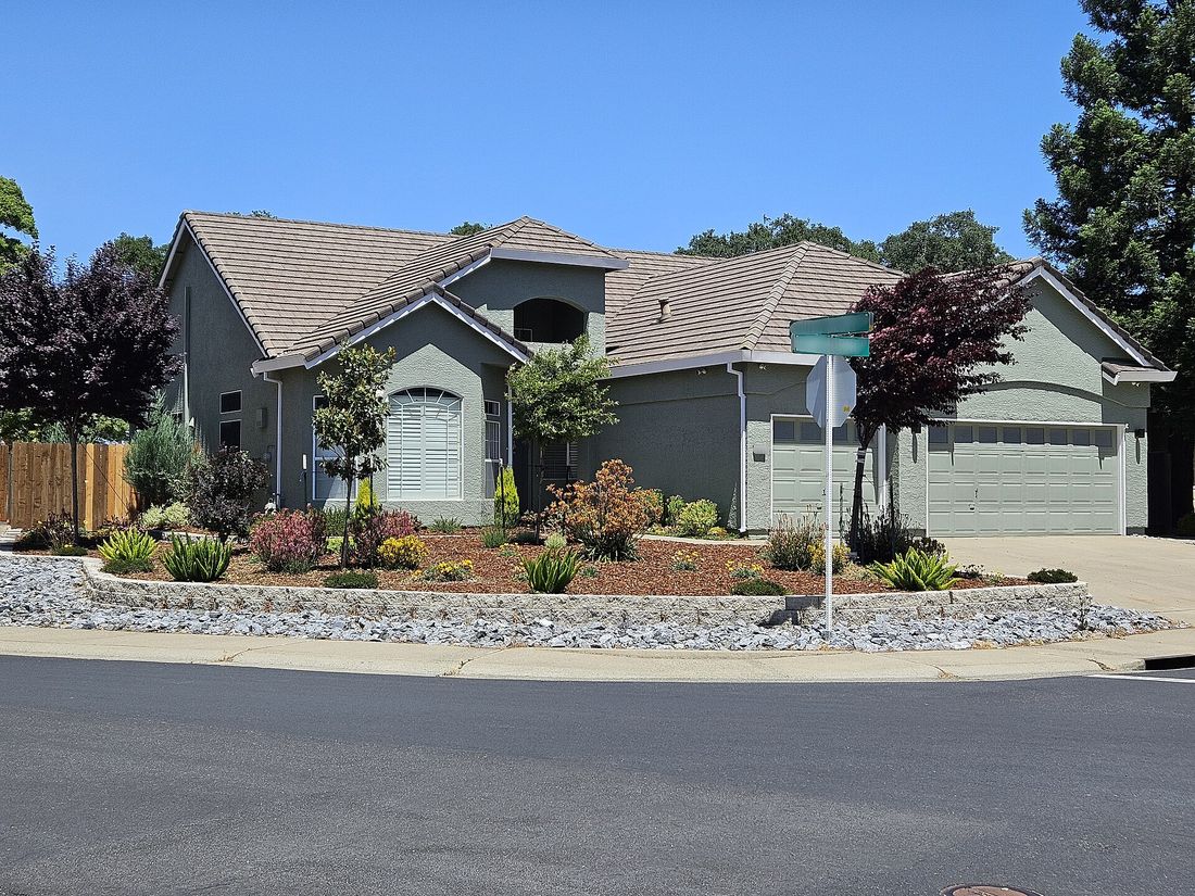 Corner-lot front yard with retaining wall, fresh mulch and colorful drought-tolerant shrubs