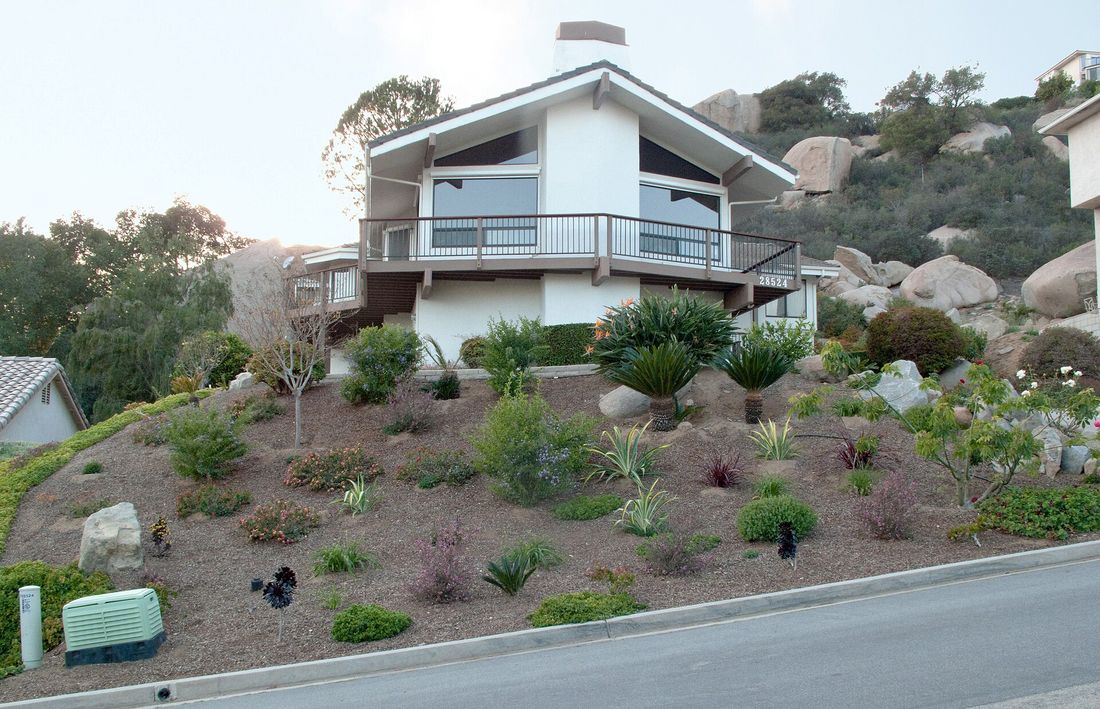 Hillside home with new drought-tolerant planting beds and boulder accents